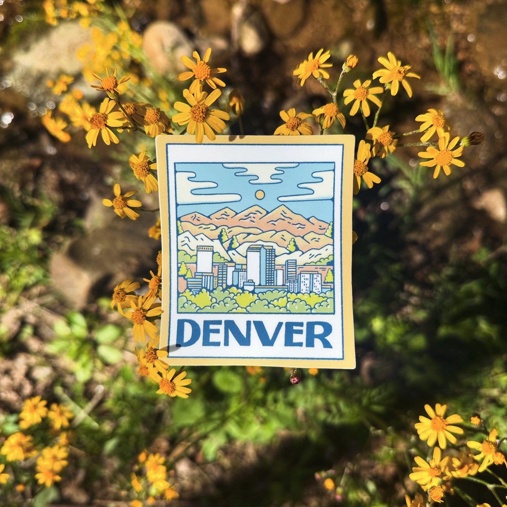 Sticker with a mountain and cityscape design surrounded by yellow flowers