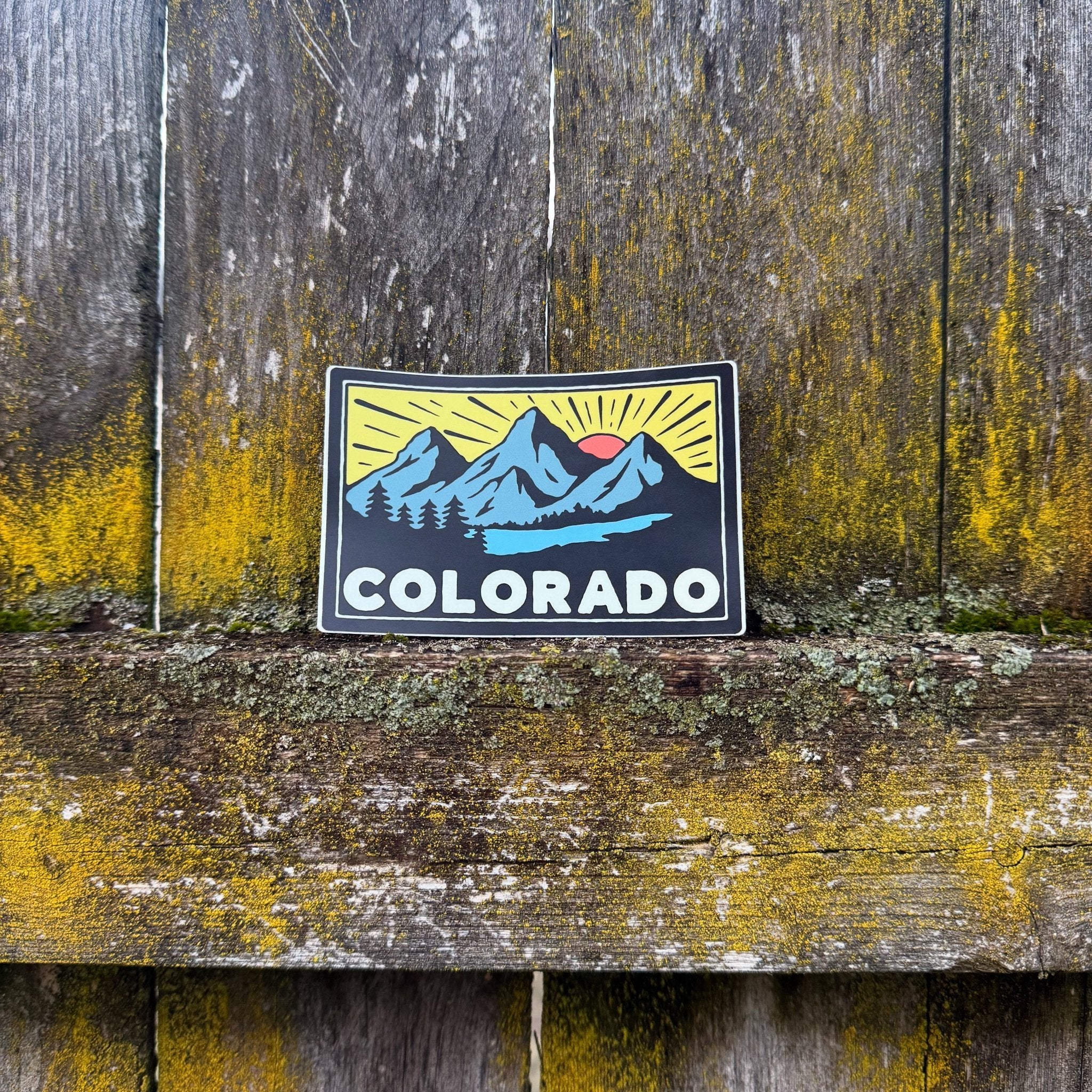 A rectangular Colorado vinyl sticker with mountain, river, sun, and trees graphic – matte finish, waterproof