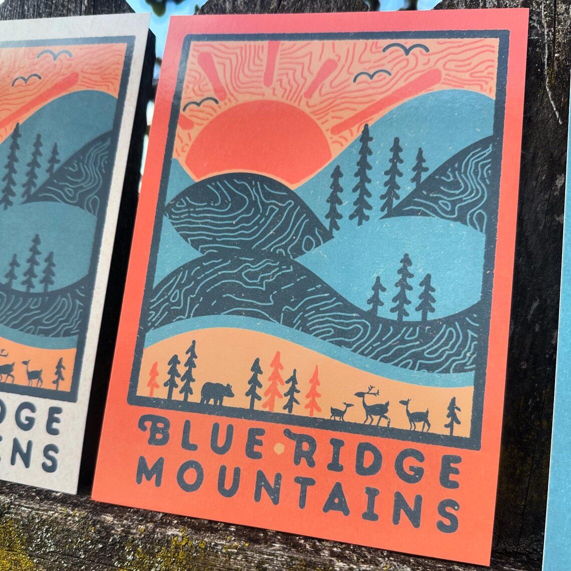 Close-up of single postcard from the set with vibrant sunrise and trees