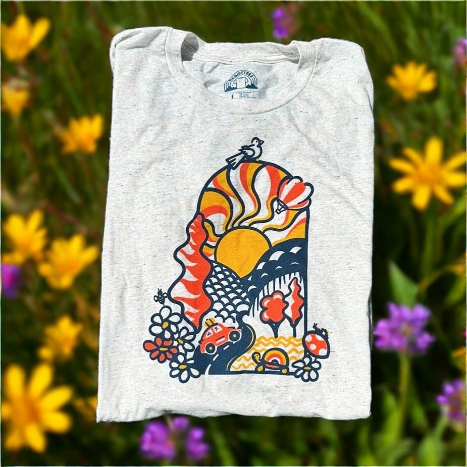 Colorful vintage-style graphic tee featuring sun, waves, and 70s-inspired patterns