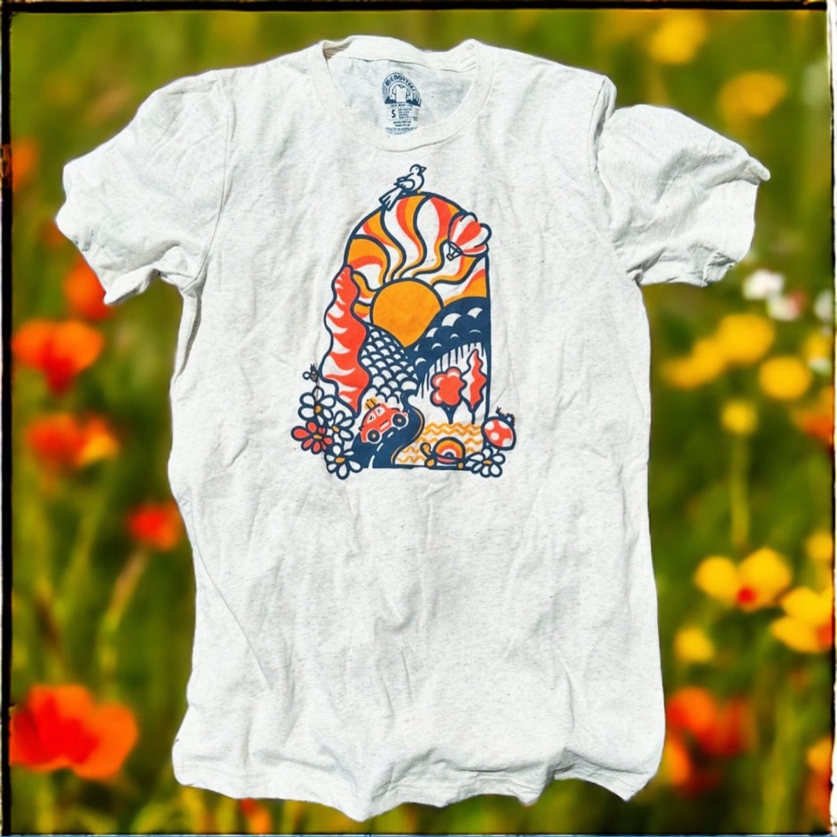 White crew neck t-shirt with a colorful abstract graphic design, displayed on a model against a floral background.