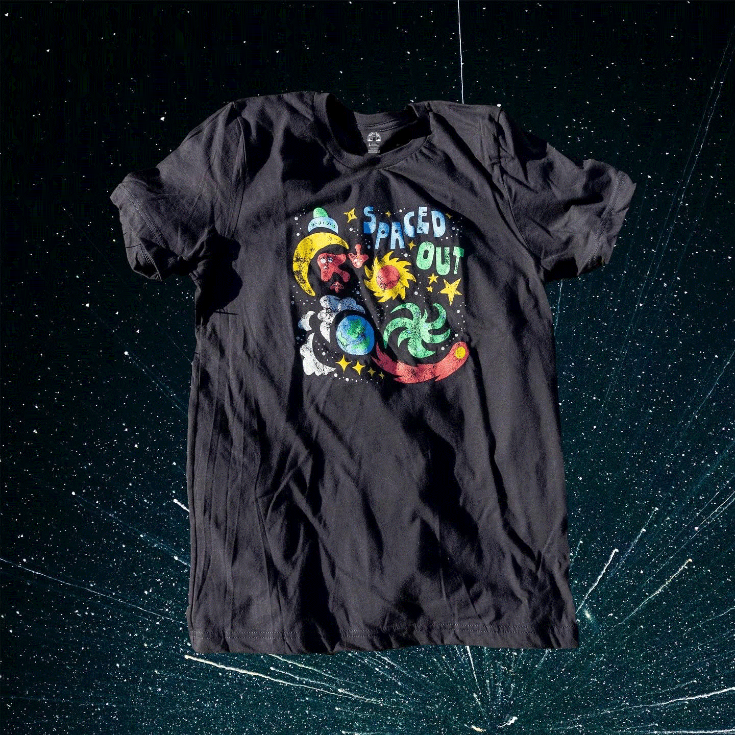 Zoomed-in view of Spaced Out tee design showing stars, planets, and bold colors