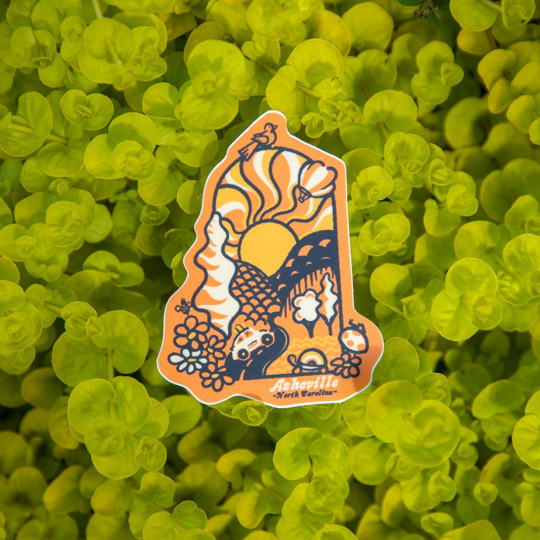 A rectangular sticker with a colorful illustration featuring floral patterns, sun and moon motifs, and the text 'Groovy Day Asheville'.