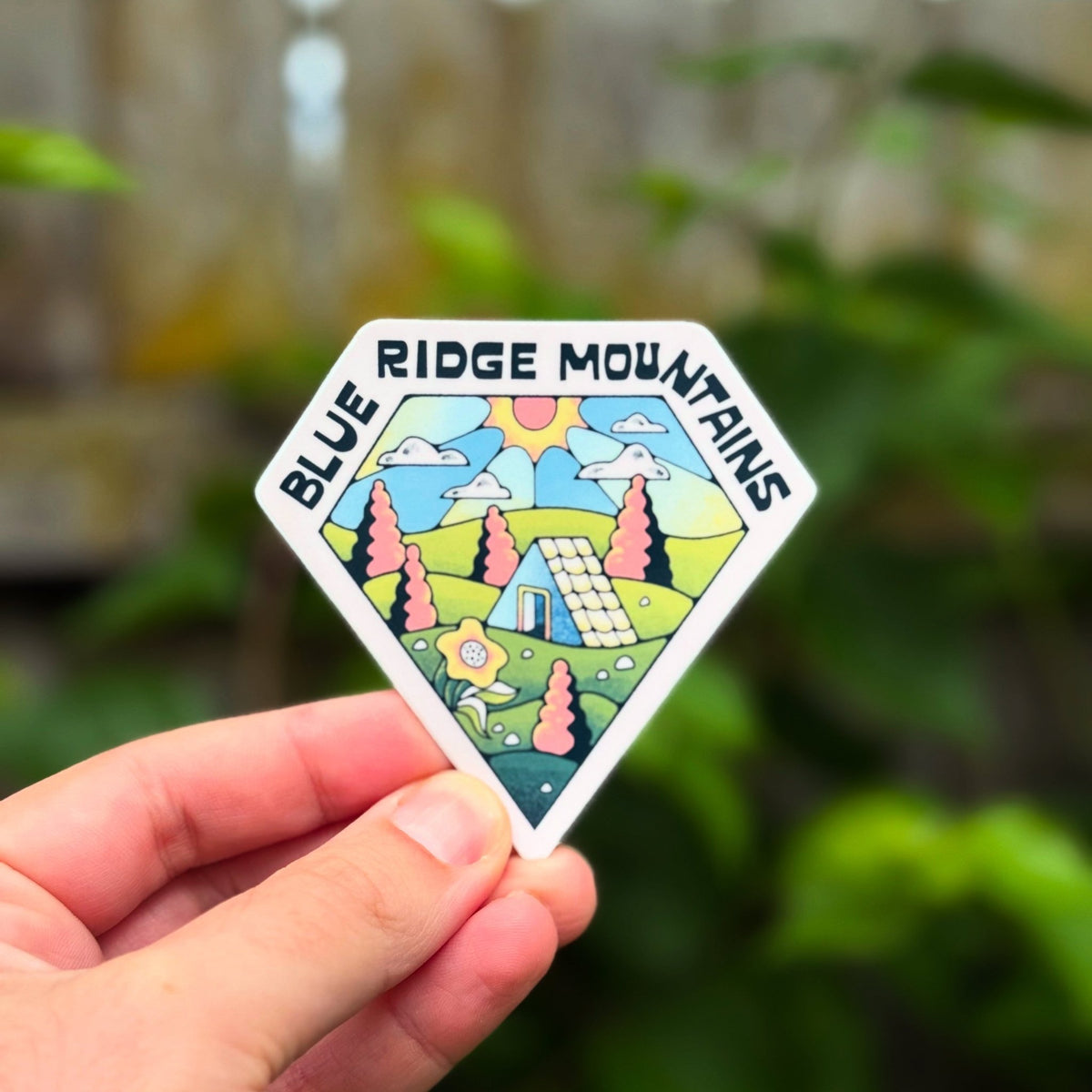 Sticker with &#39;Blue Ridge Mountains&#39; design held by a hand against a blurred natural background