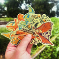 Hand holding full set of 6 colorful vinyl gnome stickers in front of train tracks