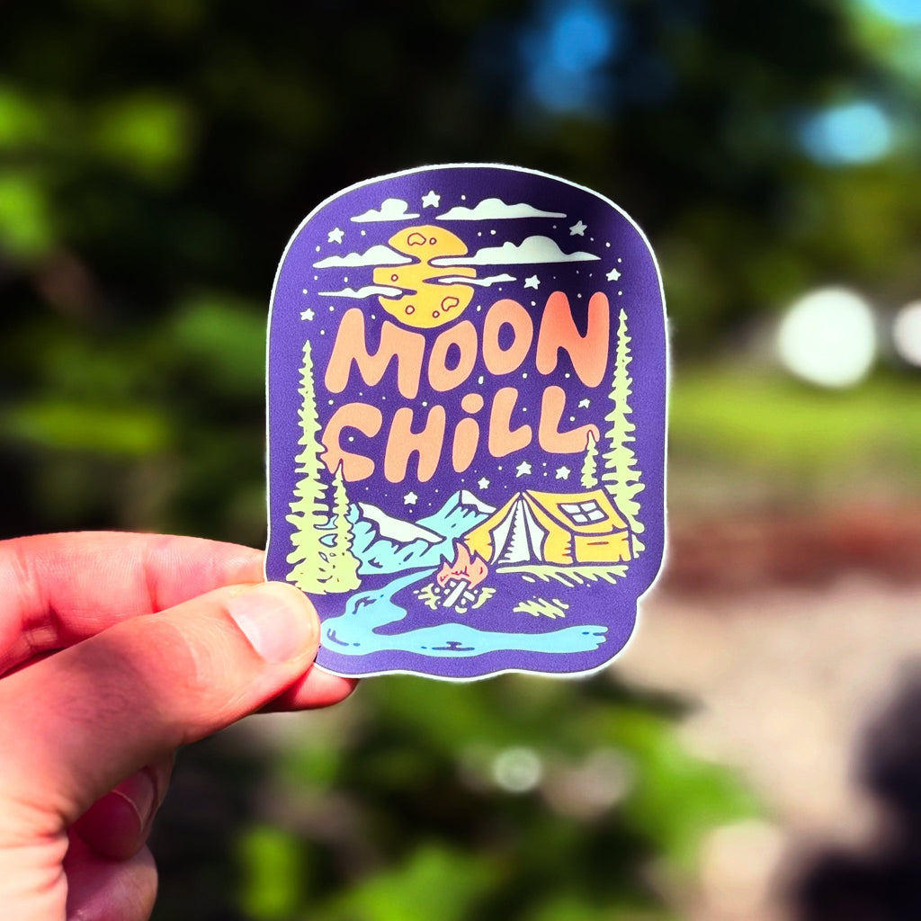 Sticker with 'Moon Chill' design held by a hand against a blurred natural background