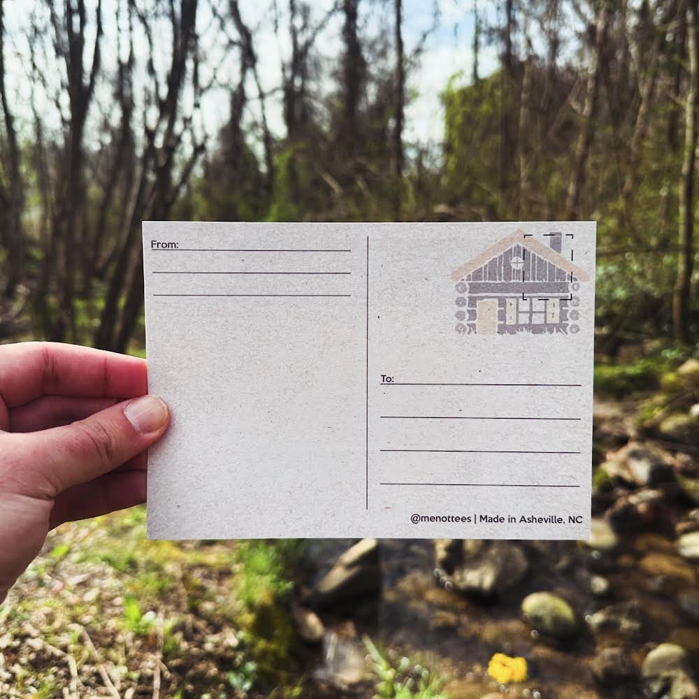 Back of the postcard with writing lines and a small icon of a cabin in the woods.

