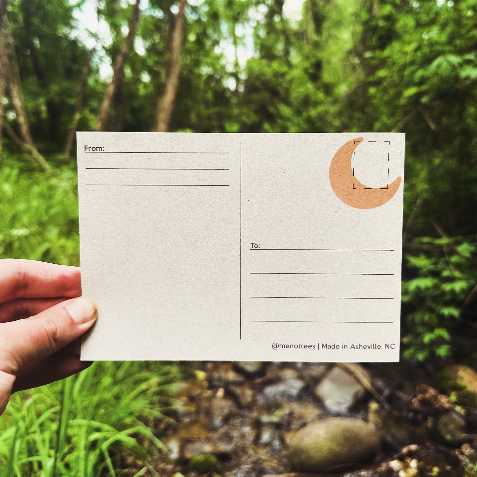 Back of the postcard with a small yellow moon design and blank space for writing and postage.

