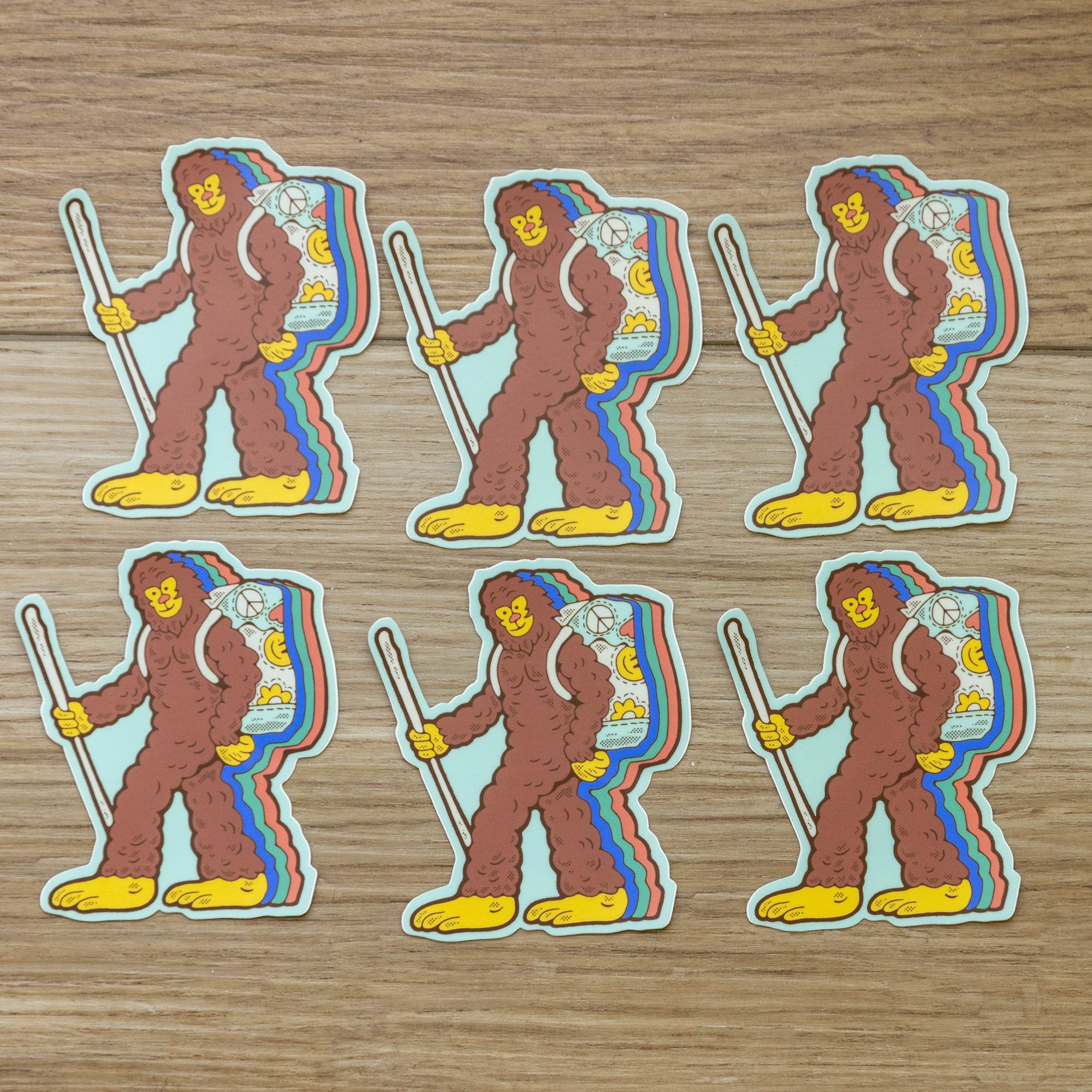 Multiple Retro Hiking Bigfoot stickers arranged flat, showing repeated colorful design.

