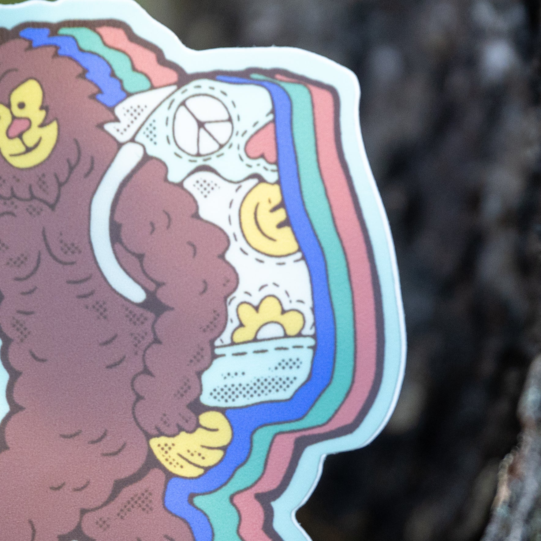 Close-up of Bigfoot’s backpack on the sticker, revealing a cheerful 70s-style sun and peace sign.

