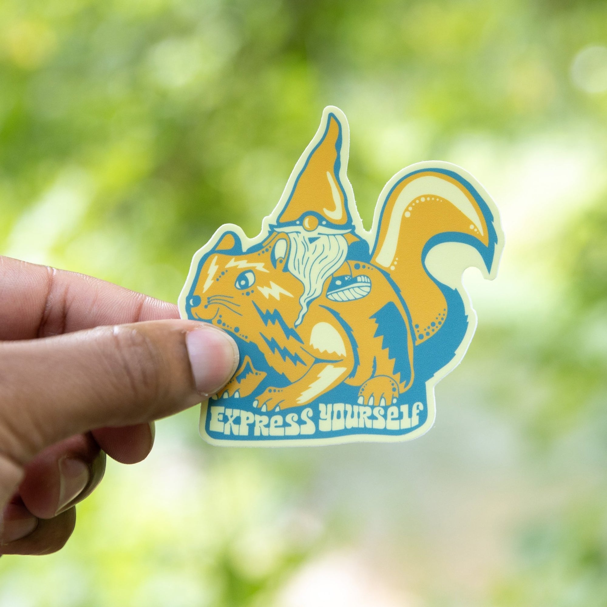 A hand holding a vinyl sticker with a colorful illustration of a gnome and the text 'Express Yourself'.