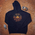 Black hoodie with a vinyl record and Mars rover illustration, laid flat on a red Martian-style surface with a robot and toy rover beside it.

