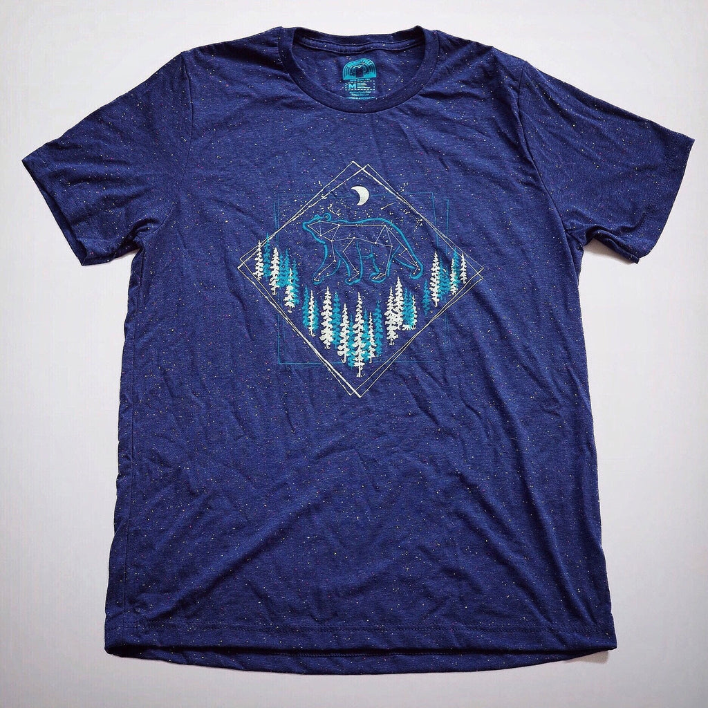 Flat-lay of navy t-shirt featuring a bear and forest graphic with moon and stars

